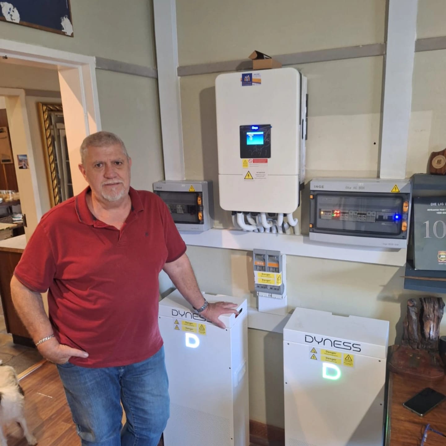 Karel, the lead installer at PRO SOLAR INSTALLER, standing next to a solar inverter and battery installation.